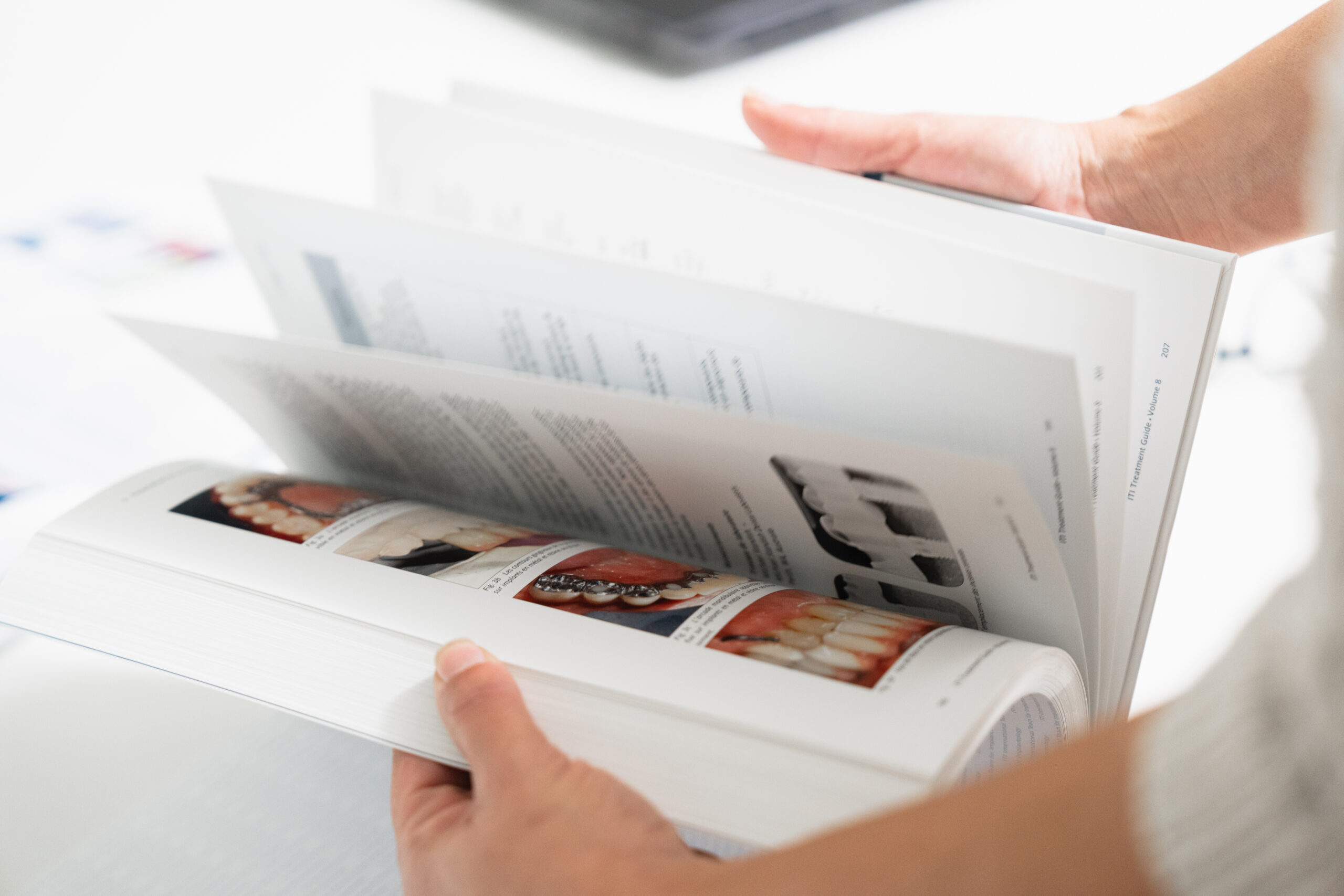 Personne feuilletant un ouvrage dentaire illustré