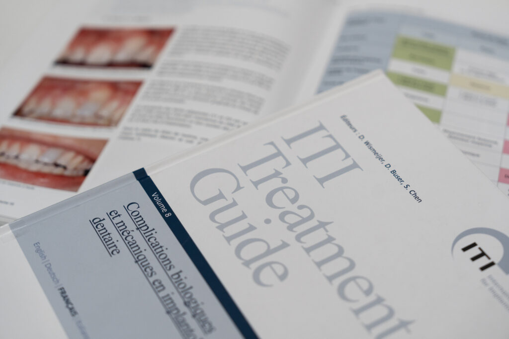 Guide ITI Treatment Guide avec pages ouvertes montrant des cas cliniques dentaires