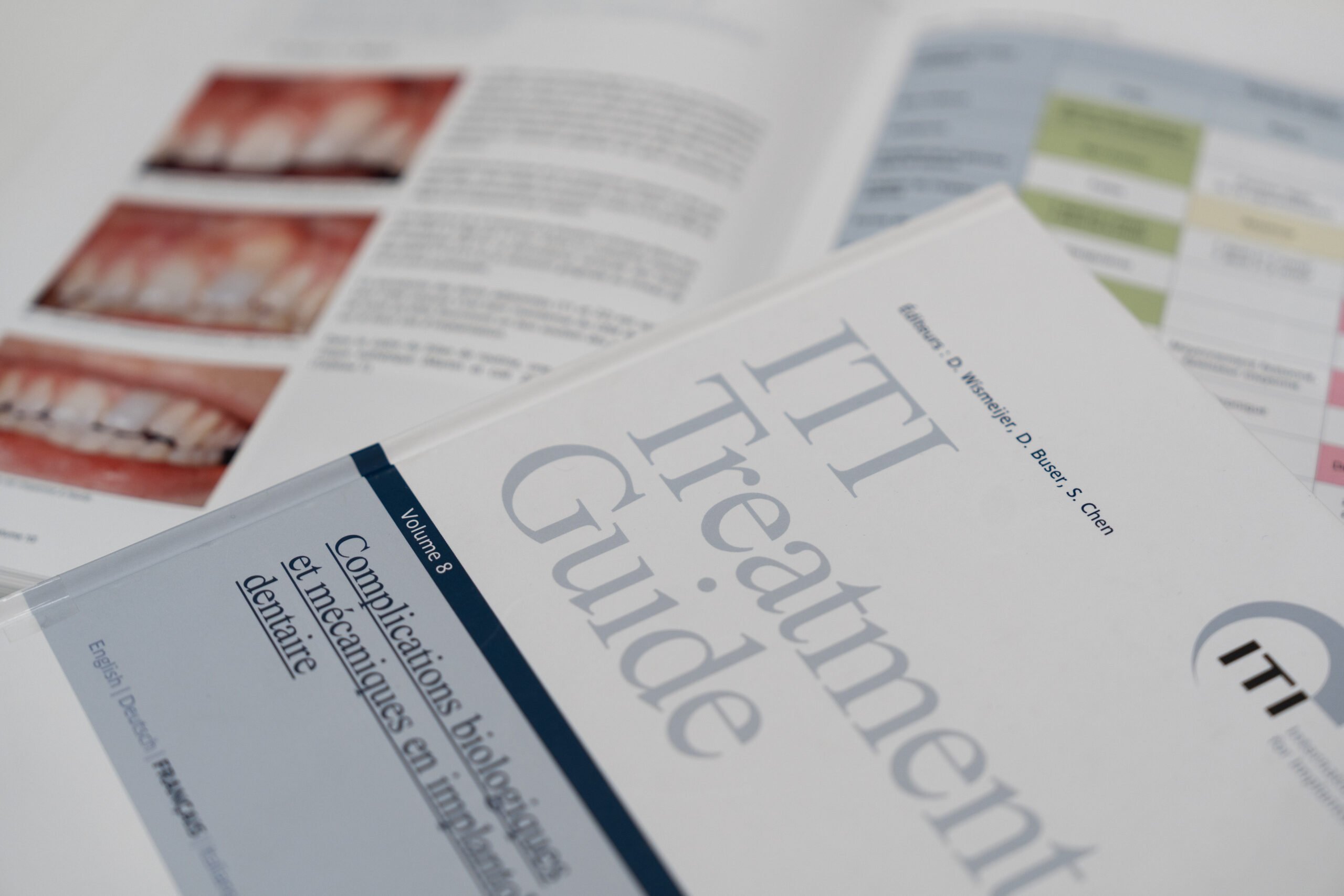 Guide ITI Treatment Guide avec pages ouvertes montrant des cas cliniques dentaires