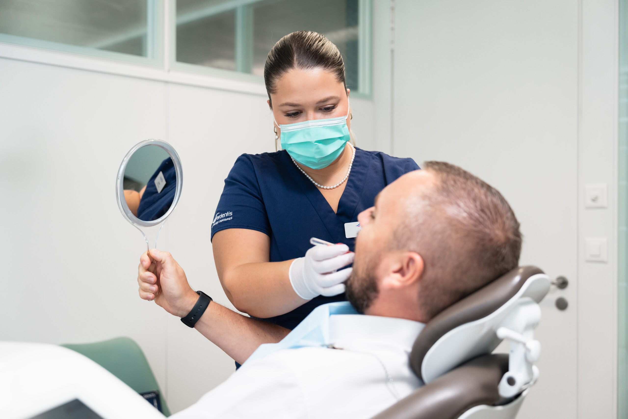 Hygiéniste dentaire réalisant un contrôle des dents d’un patient en salle de soins