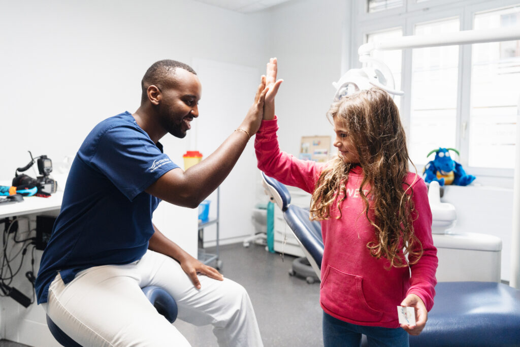 Dentiste rassurant une enfant après une consultation en cabinet dentaire